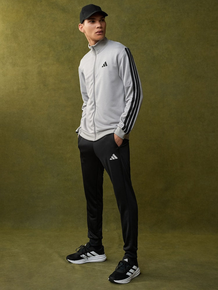 Person wearing Adidas tracksuit and cap on a green background